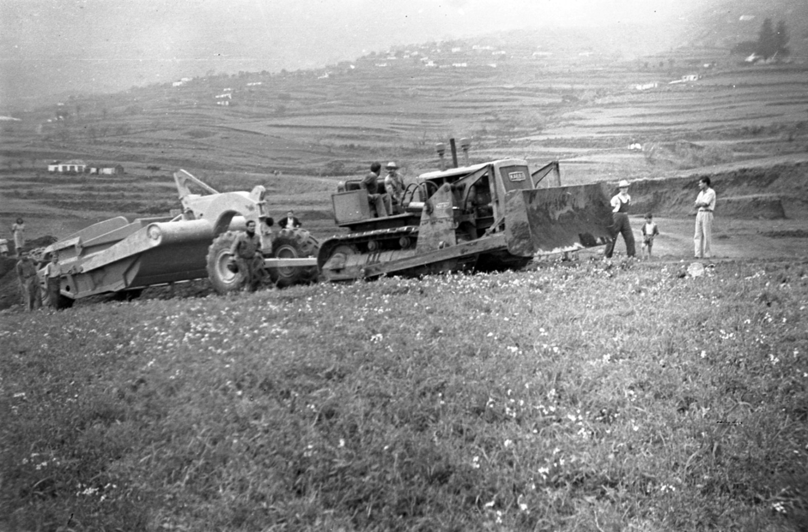 Maquinaria pesada en plena faena sobre un campo florido. Estas máquinas eran novedad en La Palma de los años cincuenta.