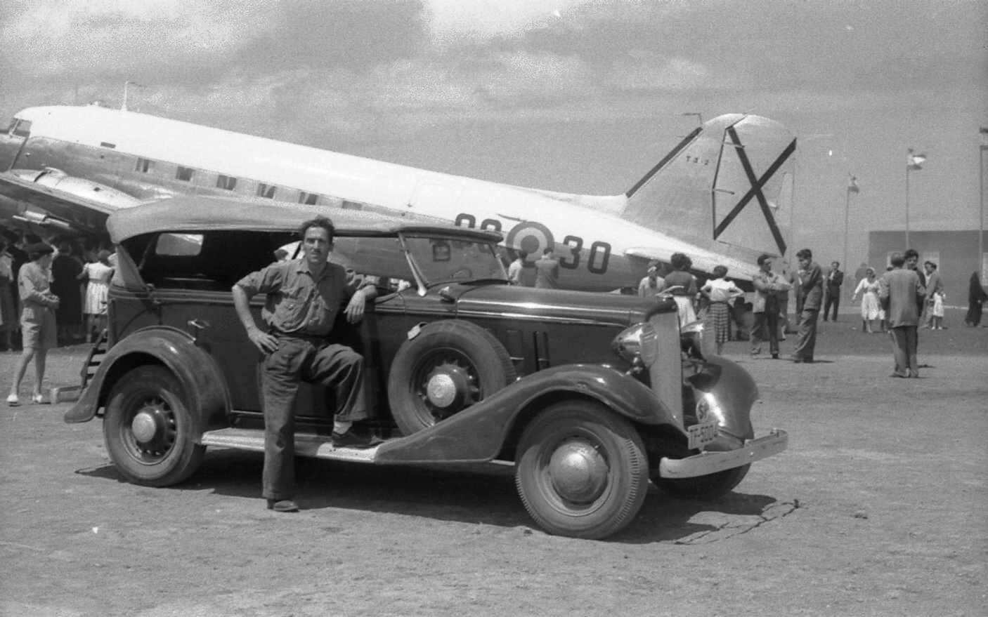 Jóvenes junto al DC-3 y un vehículo de la época