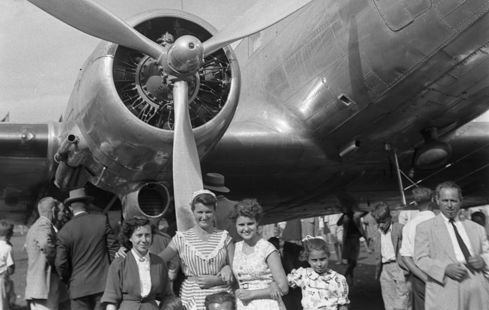 Mujeres y niña posando bajo el motor del avión