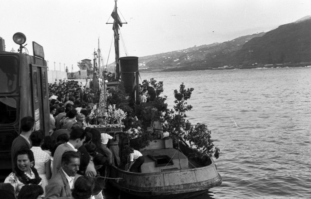 Embarque junto al muelle: una barca engalanada con flores y una multitud en el muelle