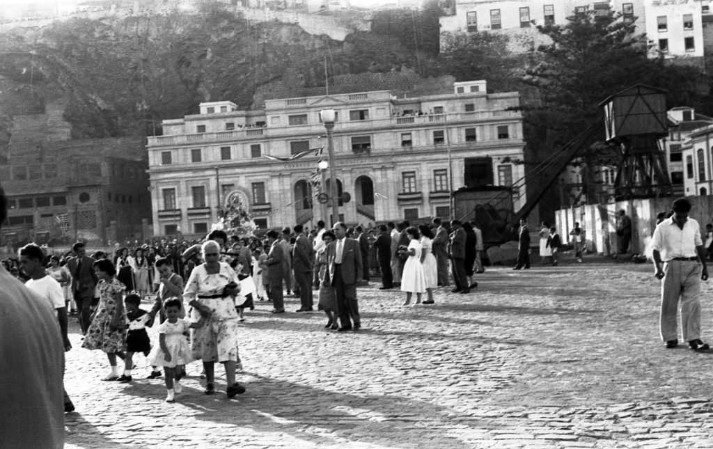 La comitiva de la procesión avanza por el frente marítimo ante un edificio señorial