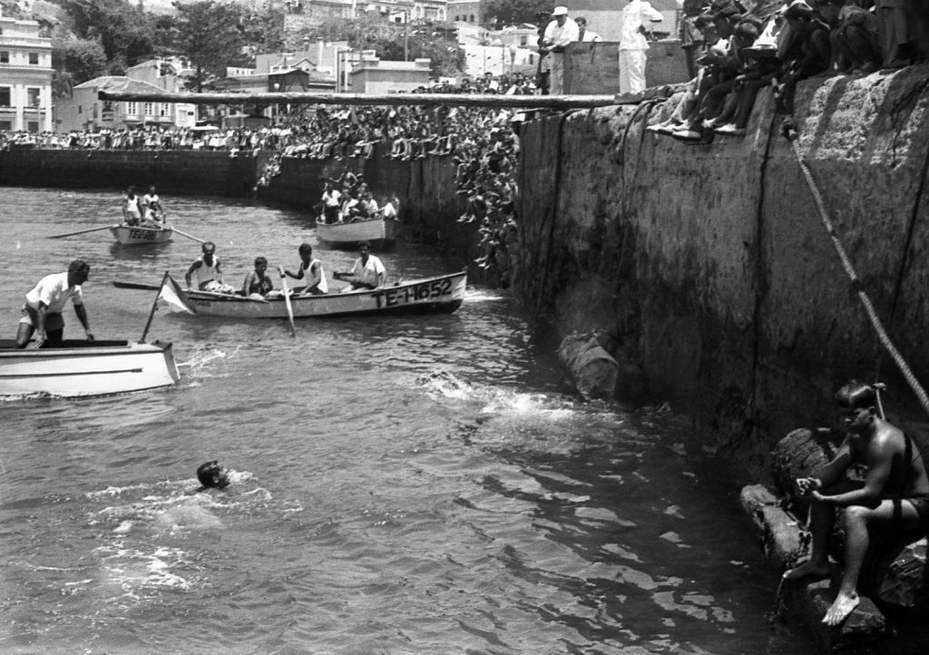 Barcas de remo bordean el muro del malecón repleto de público