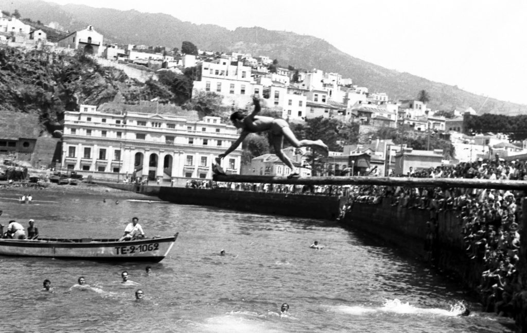 Otro clavado desde el muro ante la multitud, con una barca matrícula TE-2-1069 en el agua