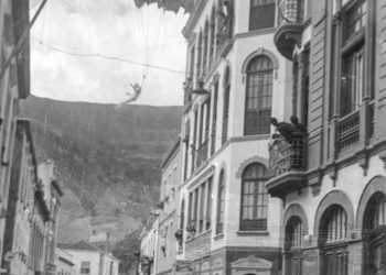 Paracaídas abriéndose en el aire entre las fachadas de la Calle Real