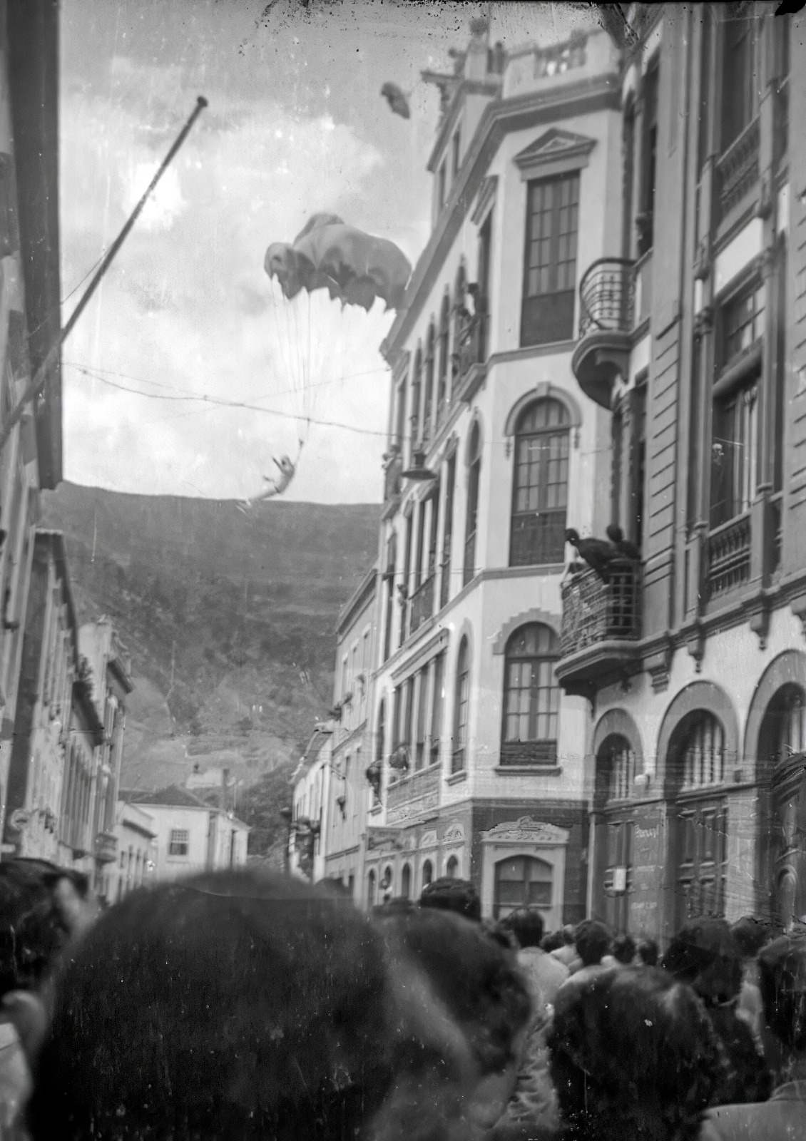 Paracaídas abriéndose en el aire entre las fachadas de la Calle Real